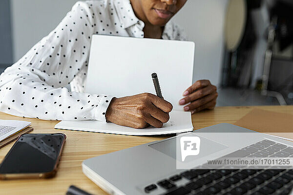 Businesswoman working in modern office with laptop using notes