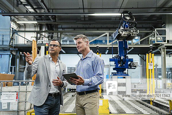 Male entrepreneur pointing while talking with supervisor in factory