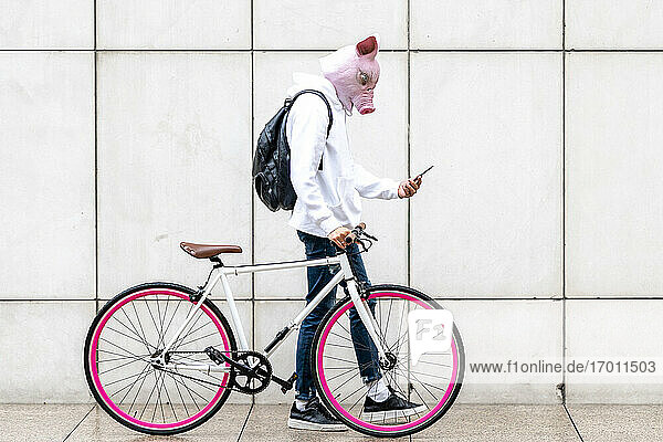 Junger Mann mit Smartphone und Fahrrad auf dem Gehweg