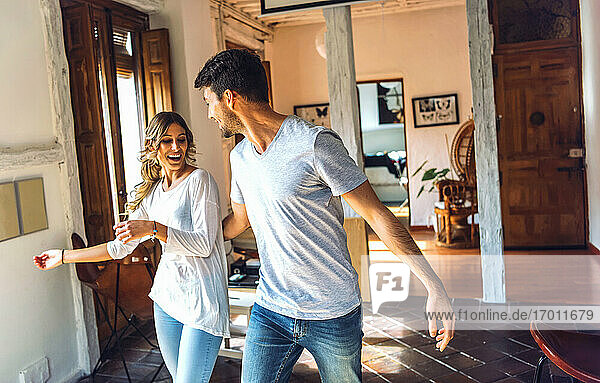 Junges Paar tanzt im Wohnzimmer zu Hause