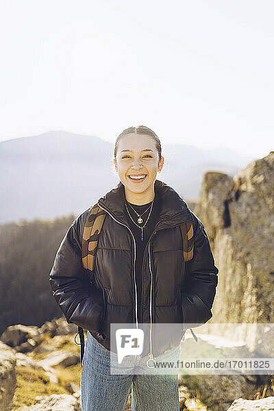 Lächelnde Wanderin auf dem Berg stehend gegen den klaren Himmel an einem sonnigen Tag
