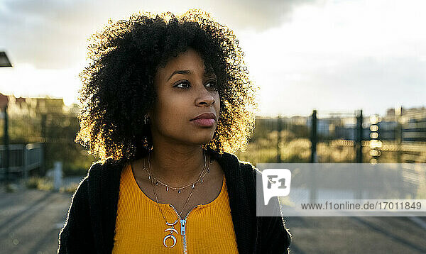 Close-up of thoughtful beautiful woman with afro hair against sky