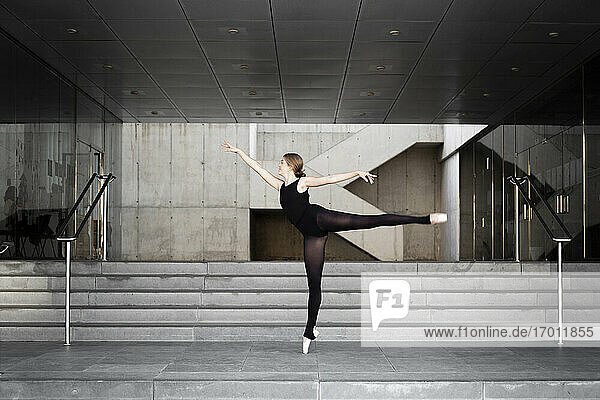 Ballerina in schwarzem Trikot in modernem Betongebäude