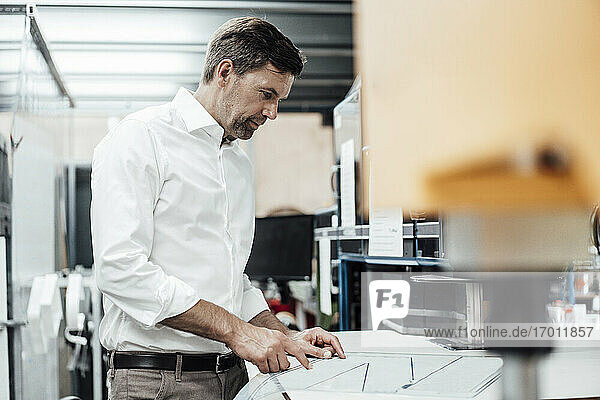 Mature businessman with business plan working while standing in industry