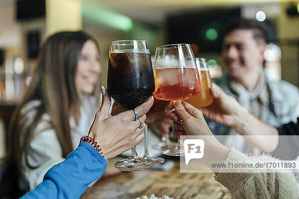 Friends toasting drink over table in bar