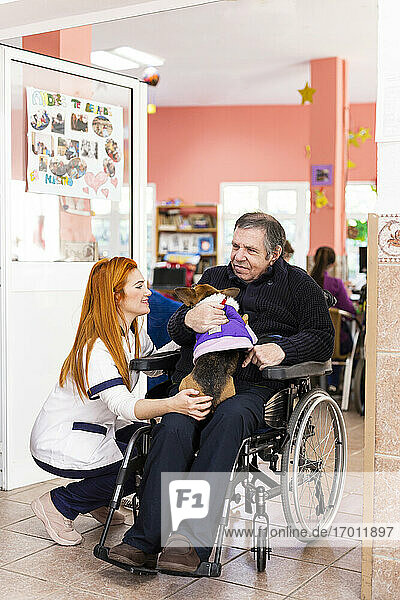 Disabled man and female nurse with pet in nursing home