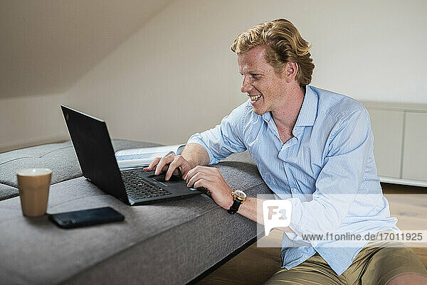 Smiling businessman working on laptop at home