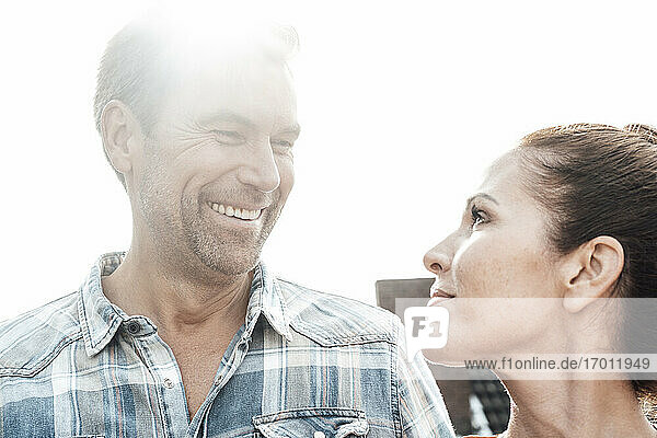 Mature happy couple looking at each other against clear sky