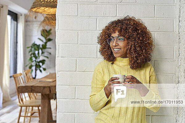 Frau schaut weg  während sie in einem Café einen Kaffee gegen eine Mauer trinkt
