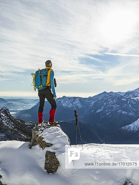 Männlicher Wanderer mit Rucksack  der die Aussicht betrachtet  während er auf dem Gipfel eines Berges steht  Orobische Alpen  Lecco  Italien