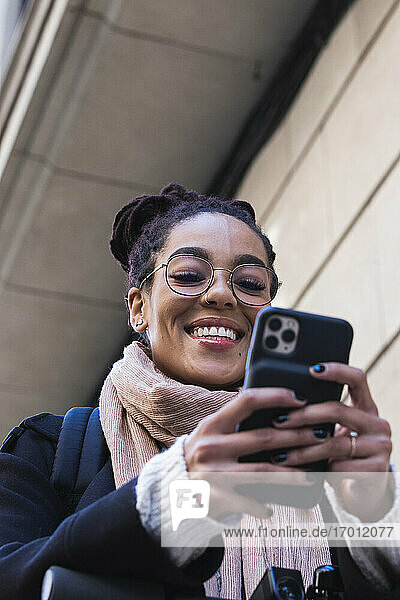 Lächelnde schöne junge Frau mit Smartphone