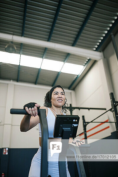 Lächelnde Sportlerin bei der Arbeit an einem Trainingsgerät im Fitnessstudio