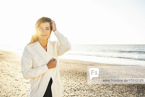 Schöne Frau steht am Strand gegen den klaren Himmel an einem sonnigen Tag