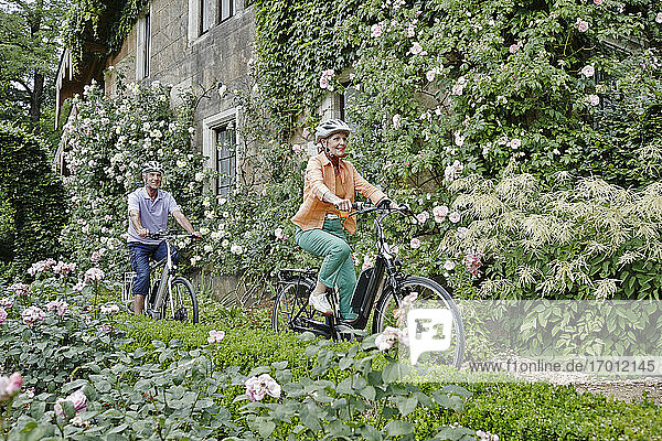Smiling couple cycling electric bicycle while exploring park at Dresden  Germany