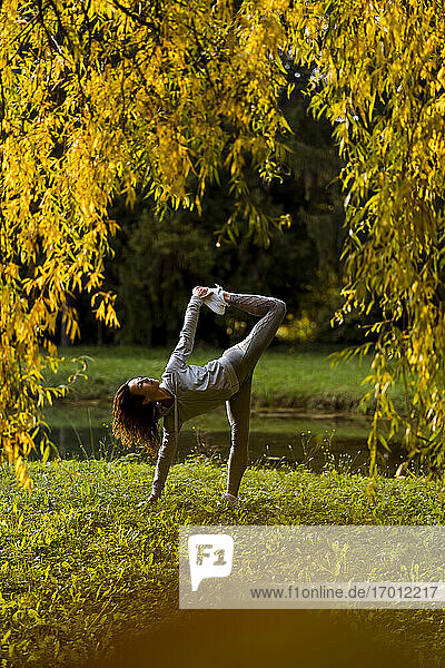 Weibliche Athletin streckt Beine und Hände beim Yoga im Park