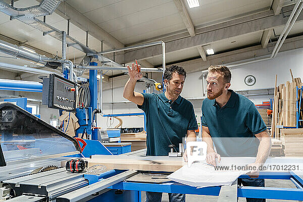 Zwei männliche Schreiner arbeiten zusammen in einer Produktionshalle