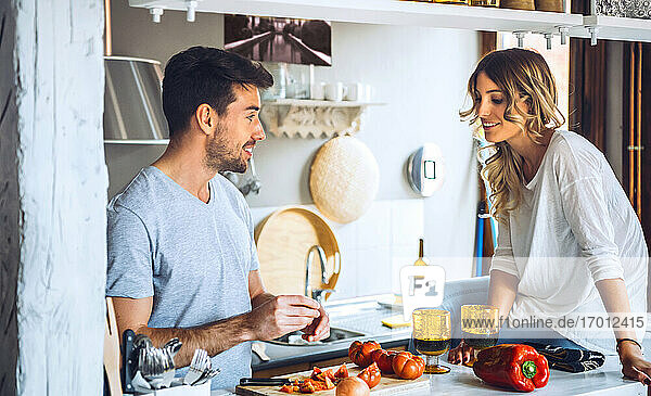 Young man preparing food with girlfriend in kitchen at home