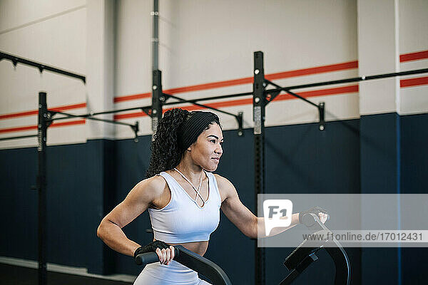 Lächelnde Sportlerin beim Training auf dem Heimtrainer im Fitnessstudio