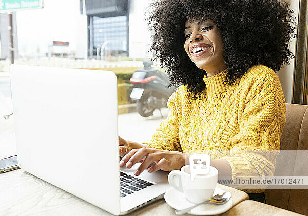 Glückliche Frau  die in einem Café sitzt und einen Laptop benutzt