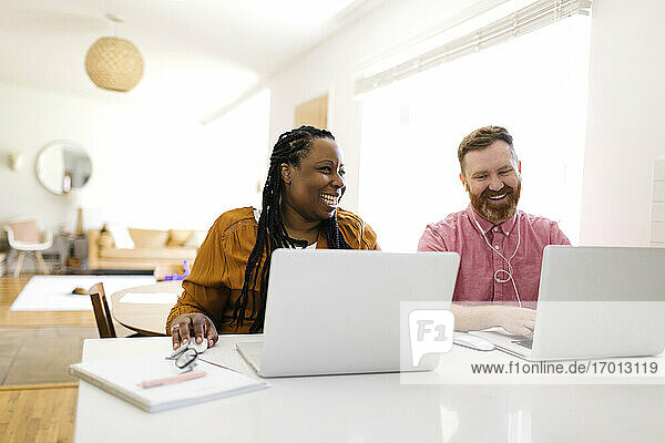 Man and woman working with laptops at home office