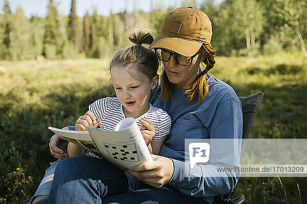 USA  Utah  Uinta National Park  Mutter und Tochter (6-7) machen Kreuzworträtsel auf einer Wiese im Wald