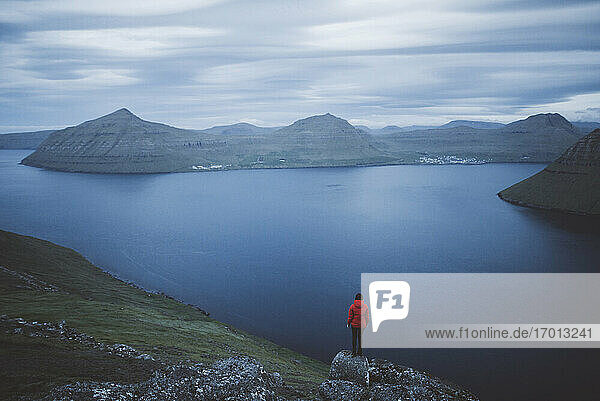 Denmark  Faroe Islands  Klaksvik  Woman standing on rock and looking at fjord