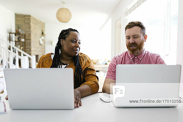 Man and woman working with laptops at home office
