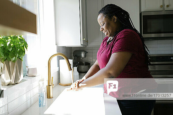 Frau wäscht Hände in der Küchenspüle