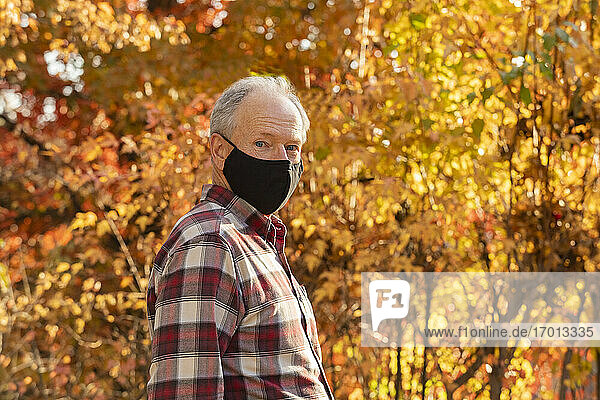 Porträt eines älteren Mannes mit Covid-Schutzmaske im Freien im Herbst