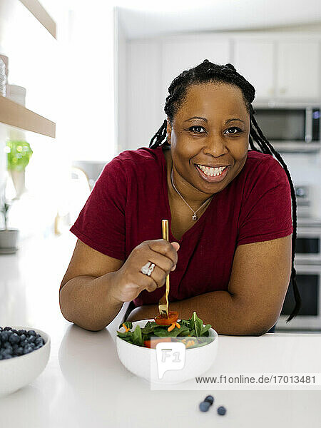 Porträt der lächelnden Frau mit gesunden Salat in der Küche