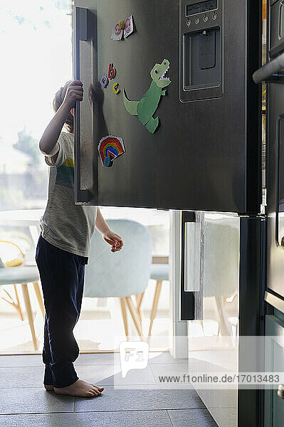 Boy (4-5) searching for food in fridge