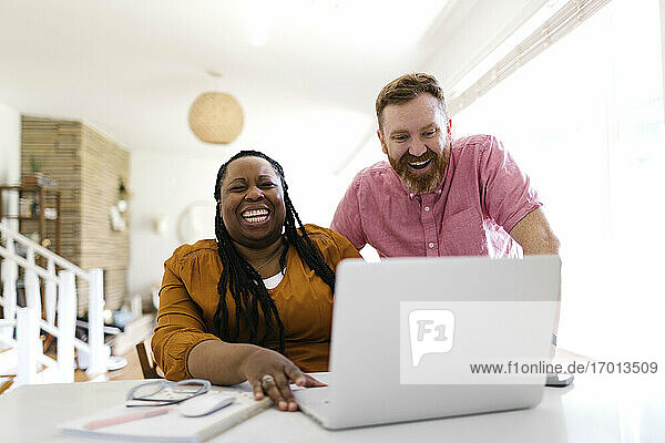Mann und Frau schauen auf Laptop am Schreibtisch im Home-Office