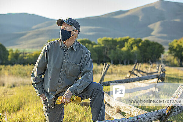 USA  Idaho  Bellevue  Farmer mit Gesichtsmaske lehnt an Zaun auf Feld