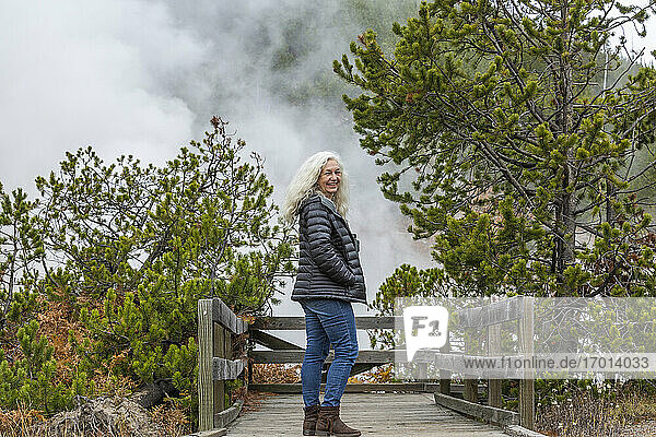 USA  Wyoming  Yellowstone National Park  Ältere weibliche Touristin steht auf hölzernem Aussichtspunkt im Yellowstone National Park