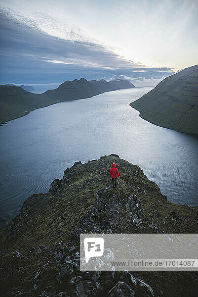 Denmark  Faroe Islands  Klaksvik  Woman standing on top of Klakkur mountain over sea and looking at view