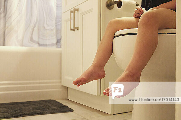 Beine von Kleinkind Mädchen (2-3) sitzen auf Toilettensitz