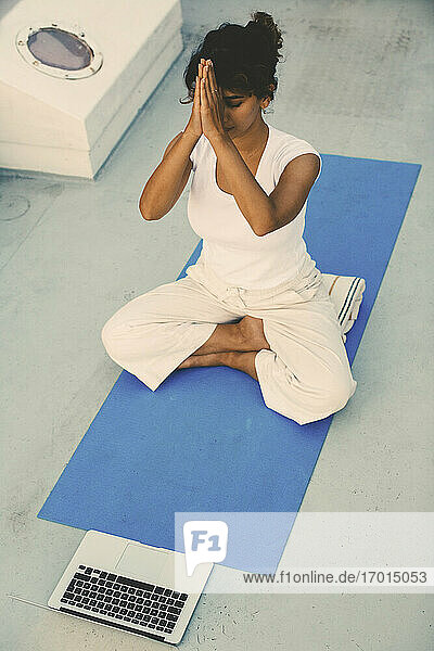 Frau e-learning Yoga Tutorial online durch Laptop auf Hausboot