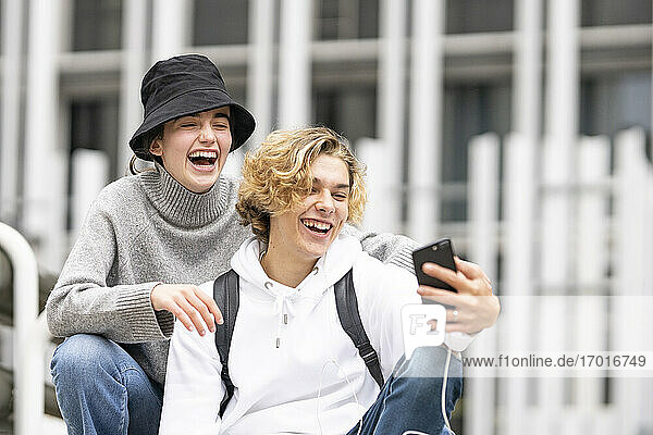 Junge Freunde lachen  während sie ein Selfie mit dem Handy machen