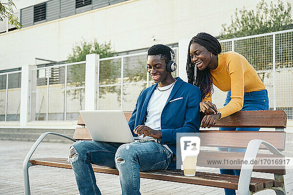 Glückliches Paar schaut auf Laptop auf Bank