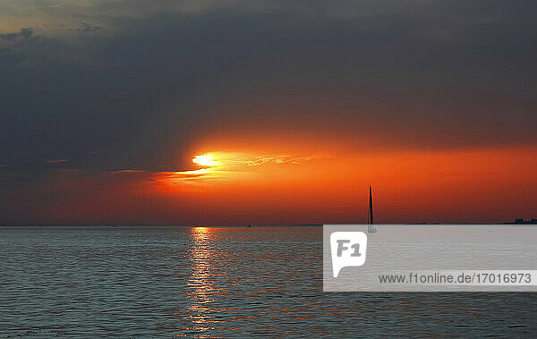 Silhouette of sailboat sailing in Lake Constance at moody sunset