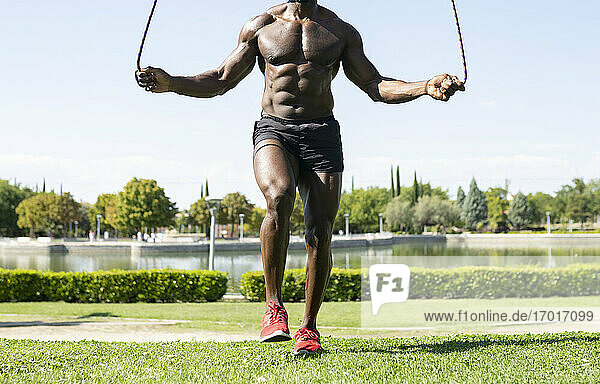 African male athlete doing skipping exercise in park on sunny day