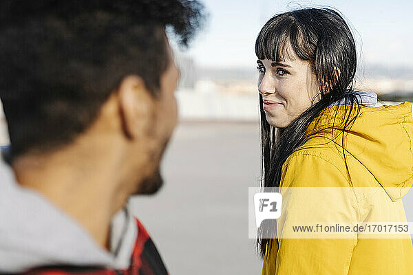 Smiling woman looking at male friend while standing outdoors