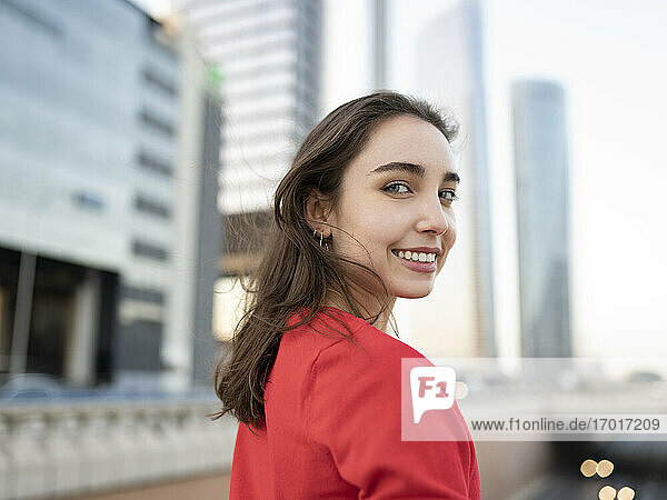 Smiling woman looking over shoulder in city