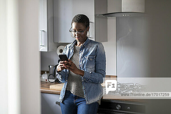 Frau schaut in der Küche auf ihr Smartphone