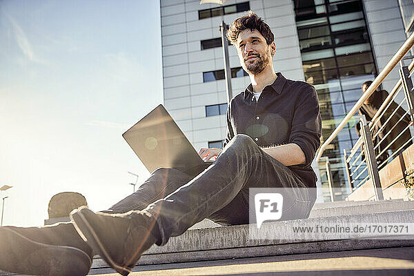 Entrepreneur using laptop while sitting on steps