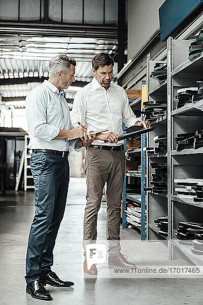 Male inspectors checking equipment while standing in workshop at industry