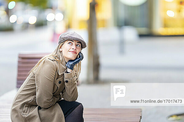 Thoughtful woman looking up while sitting on bench