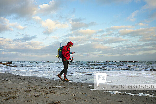 Mann benutzt Smartphone beim Spaziergang am Strand  Mittelmeer  Italien