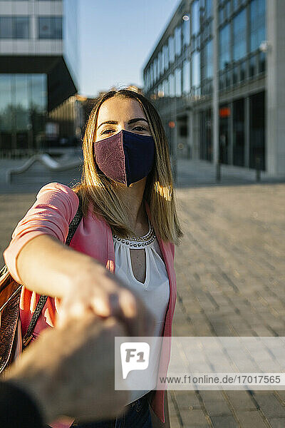 Frau mit Gesichtsmaske  die eine Person mit einem Faustschlag in der Stadt begrüßt