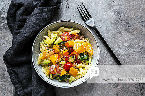 Bowl of vegan pasta with pumpkin  tomatoes and zucchini